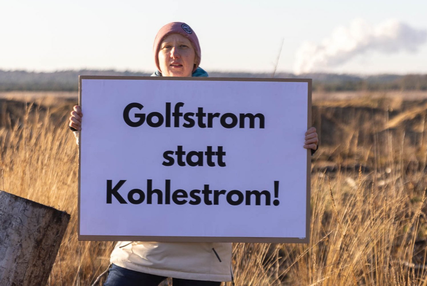 Protest am Tagebau Nochten, Plakat mit Aufschrift: "Golfstrom statt Kohlestrom!", im Hintergrund sind Rauchschwaden zu erkennen.