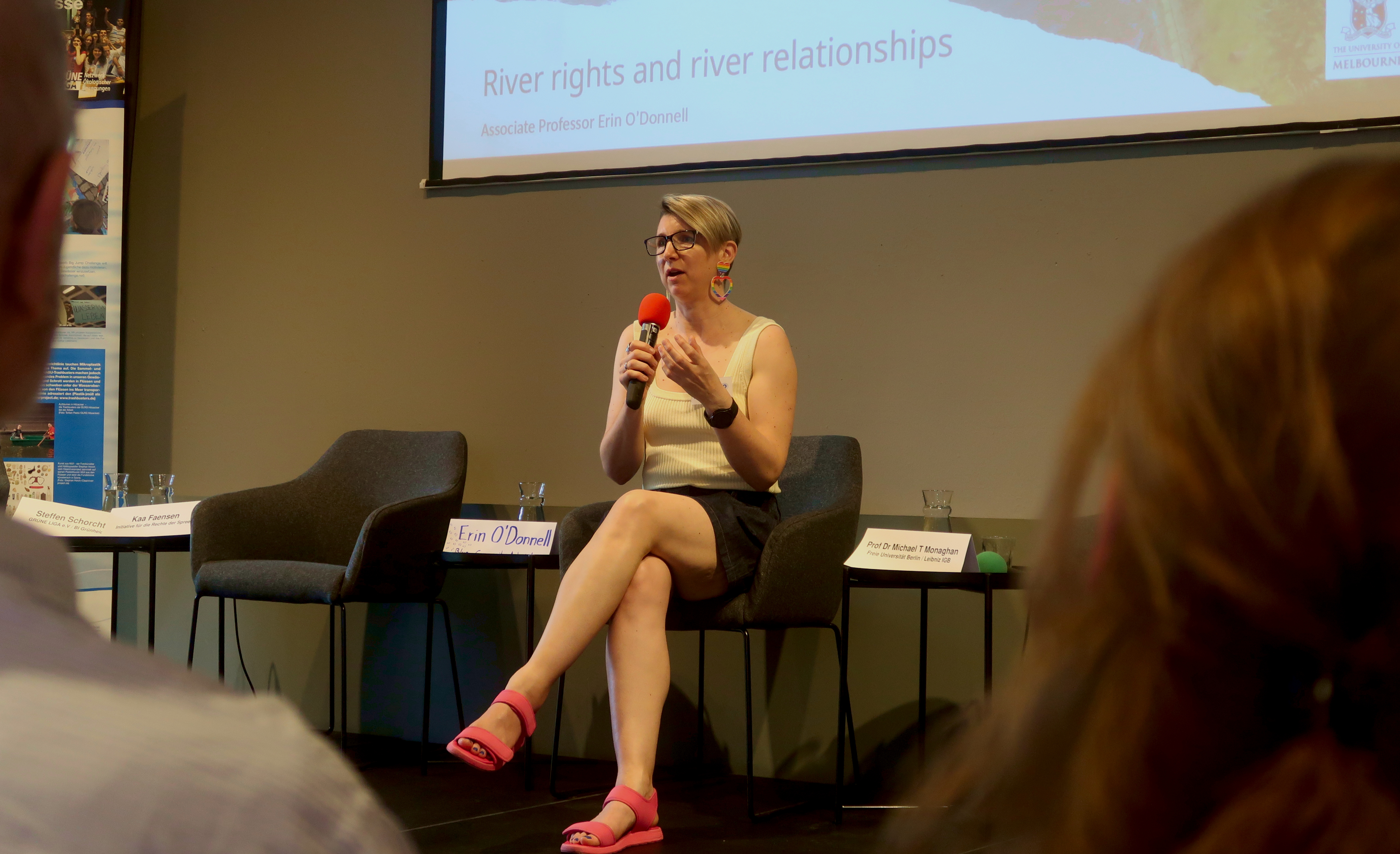 Erin O'Donnell is sitting on a chair on stage and giving her presentation.